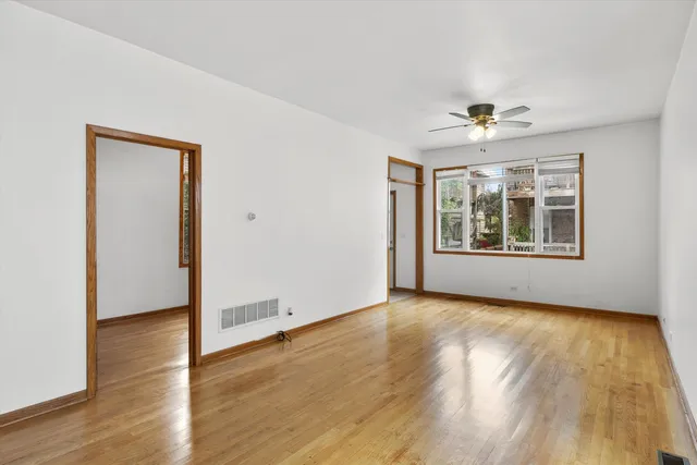 an empty room with wooden floor chandelier and windows
