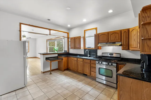 a kitchen with stainless steel appliances granite countertop a stove a sink and a refrigerator