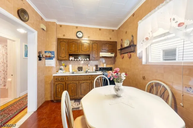 a kitchen with stainless steel appliances a sink a stove a microwave a dining table and chairs with wooden floor