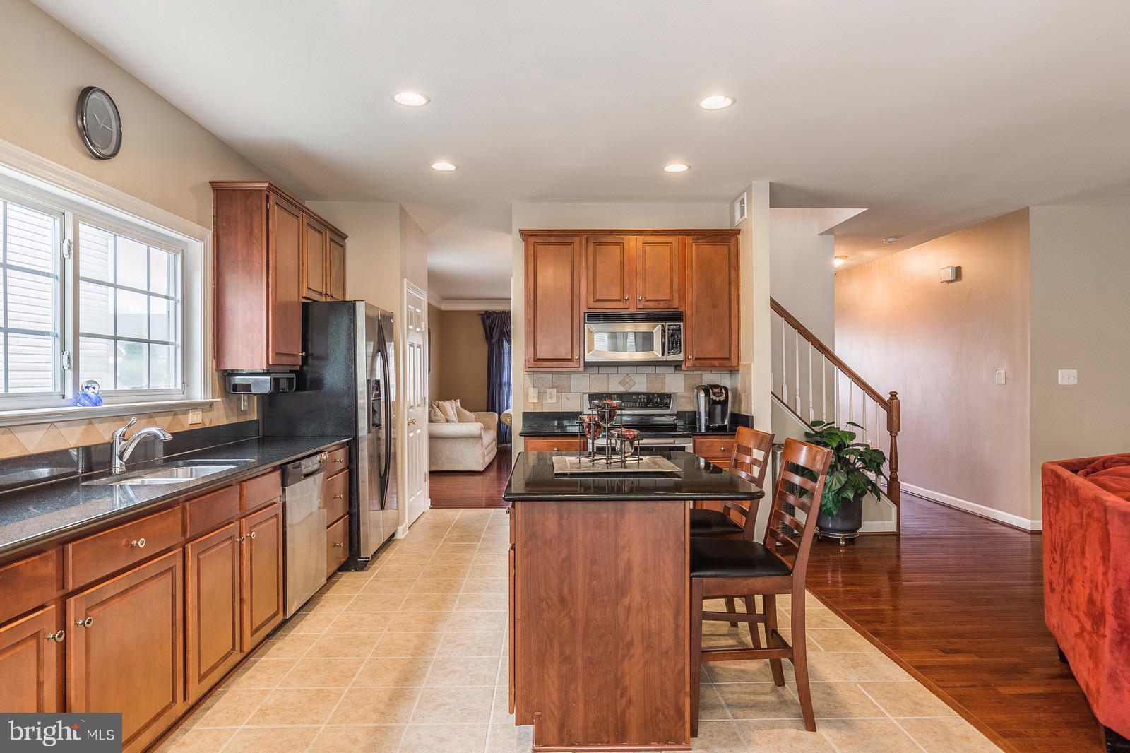 4157 Agency Loop Triangle, VA 22172 - Photo 2 of 30 a open kitchen with stainless steel appliances granite countertop a stove top oven a sink a dining table and chairs with wooden floor