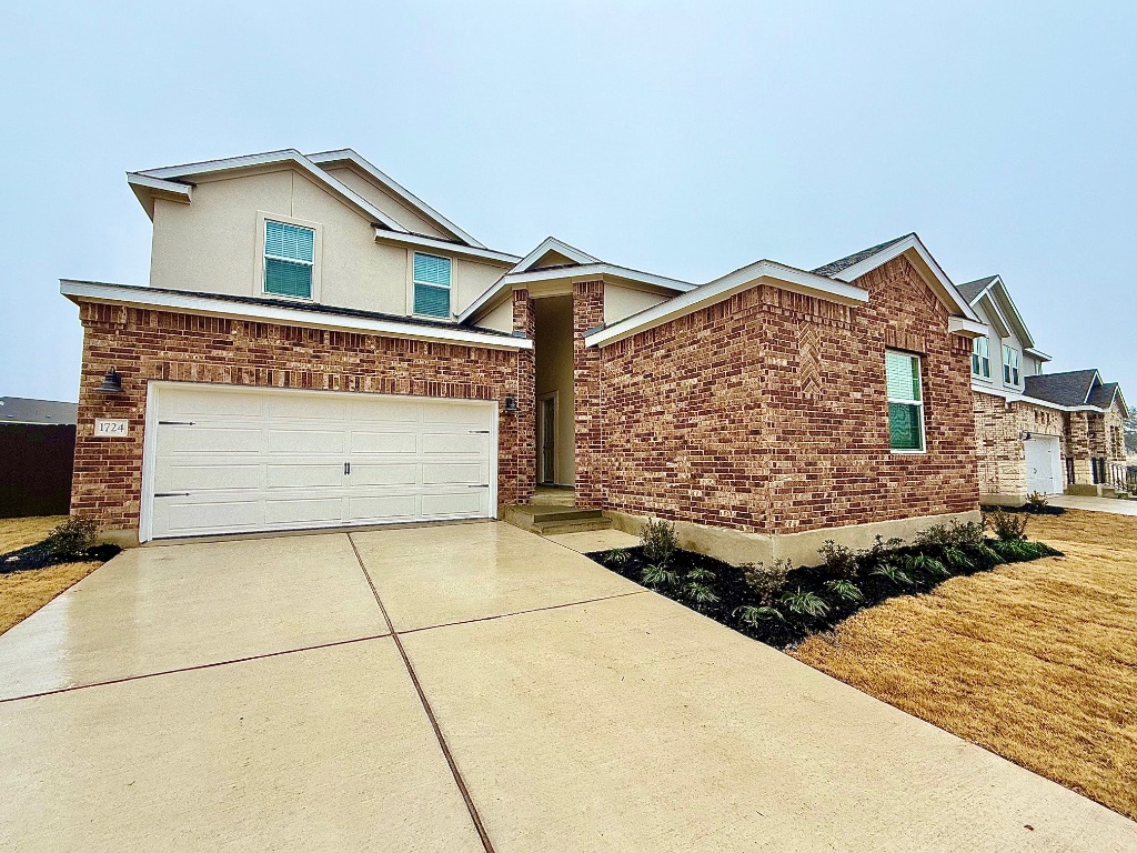 1724 Four Waters Loop Georgetown, TX 78628 - Photo 1 of 38 View of front of home with long driveway, a garage, brick siding, and stucco siding