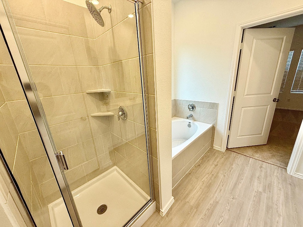 1724 Four Waters Loop Georgetown, TX 78628 - Photo 12 of 38 Primary Bathroom with a garden tub, light wood-type flooring, and a shower stall