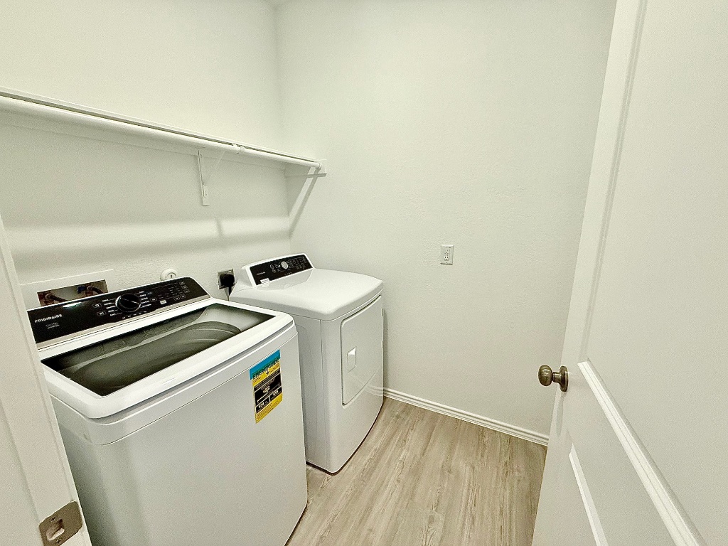 1724 Four Waters Loop Georgetown, TX 78628 - Photo 22 of 38 Laundry Room with light wood-style flooring and washer and clothes dryer