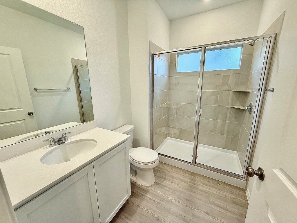 1724 Four Waters Loop Georgetown, TX 78628 - Photo 27 of 38 Gen X Full bath en suite with vanity, light wood-style flooring, and a stall shower