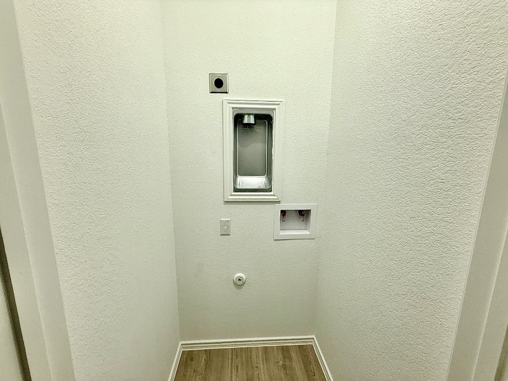 1724 Four Waters Loop Georgetown, TX 78628 - Photo 28 of 38 Gen X suite Laundry room featuring wood finished floors, a textured wall, ready for a stack washer and electric dryer hookup.