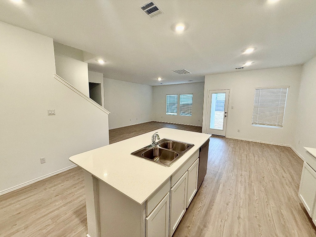 1724 Four Waters Loop Georgetown, TX 78628 - Photo 38 of 38 Kitchen featuring light countertops, open floor plan, white cabinets, a kitchen island with sink, and light wood-style flooring