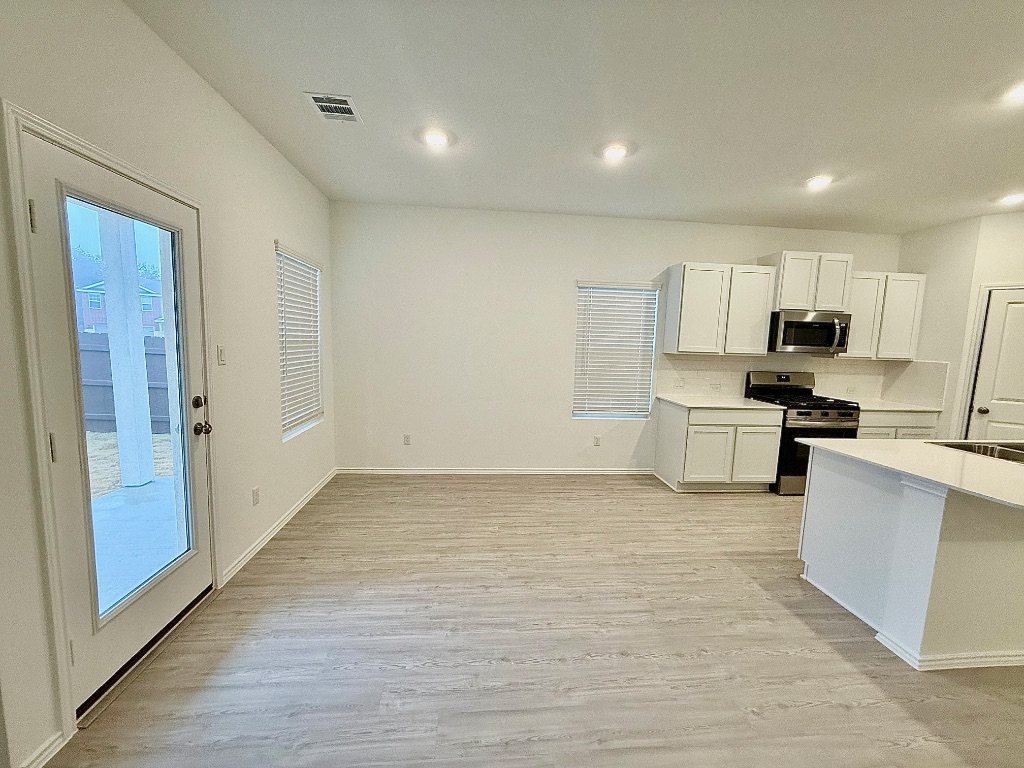 1724 Four Waters Loop Georgetown, TX 78628 - Photo 7 of 38 Kitchen with stainless steel appliances, white cabinetry, light wood finished floors, tasteful backsplash, and recessed lighting