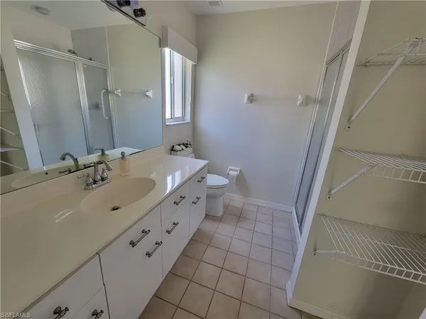 a bathroom with a double vanity sink a toilet and shower