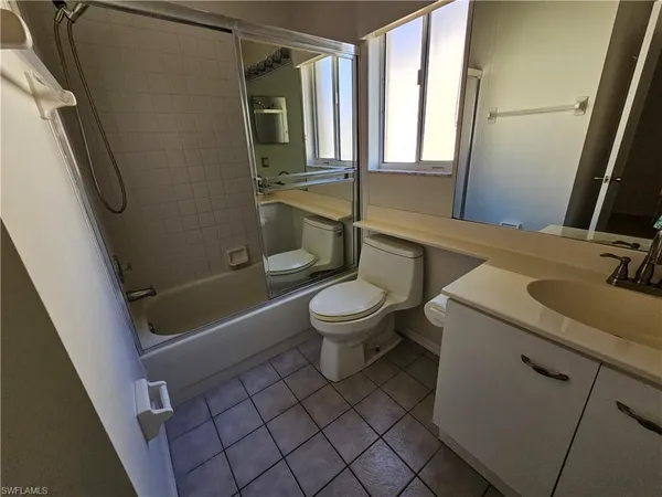 a bathroom with a sink a toilet a window and shower