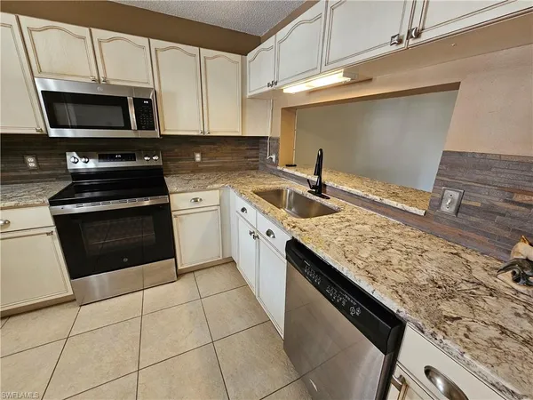 a kitchen with stainless steel appliances granite countertop a sink stove and microwave