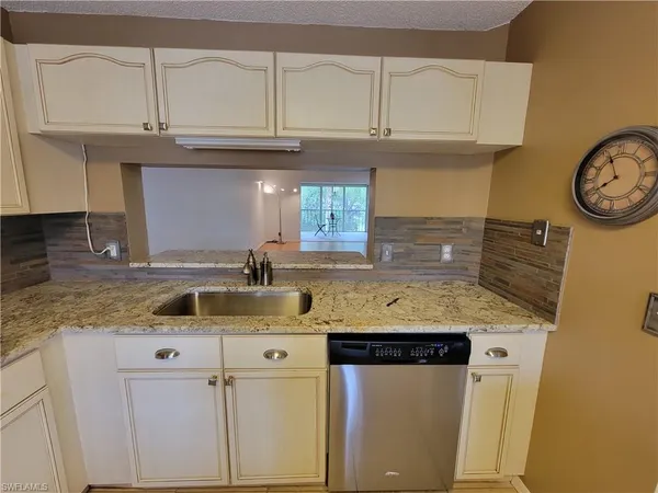 a kitchen with granite countertop a sink a stove and cabinets