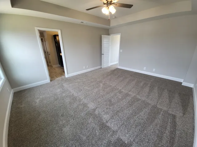 an empty room with a chandelier fan and a large mirror