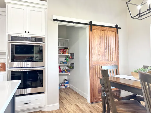 a large kitchen with stainless steel appliances kitchen island a large counter tops a stove a sink dishwasher a oven and a dining table with wooden floor