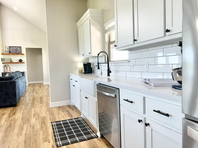 a kitchen with granite countertop white cabinets and stainless steel appliances