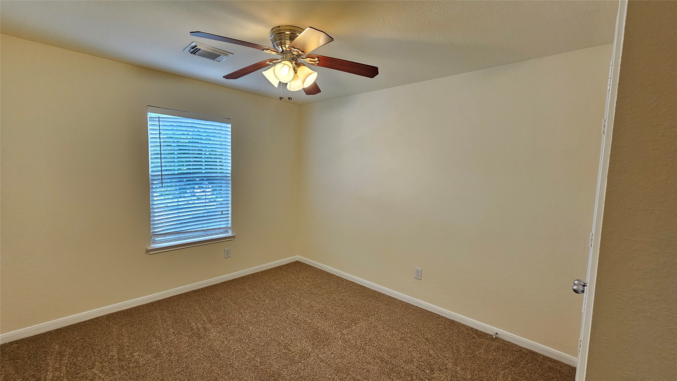 7918 Barnes Ridge Lane Houston, TX 77072 - Photo 14 of 34 This room features neutral walls and carpet, a ceiling fan with lights, and a single window with blinds, offering a cozy and simple space.