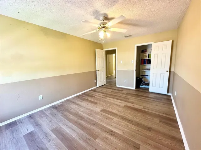 a view of a room with wooden floor and a ceiling fan
