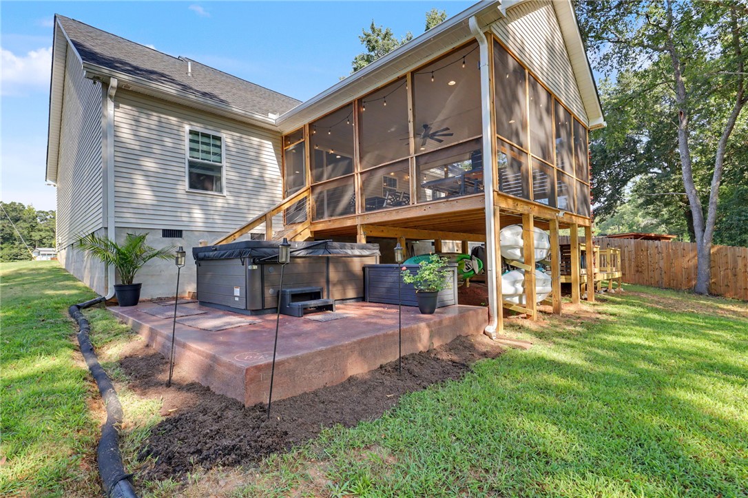 A spacious screened porch overlooks the backyard, with a covered patio, kayak storage and a hot tub that conveys with the home.