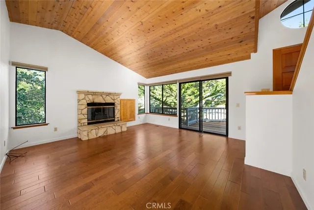 an empty room with wooden floor fireplace and windows