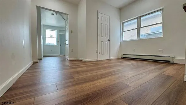 an empty room with wooden floor and windows