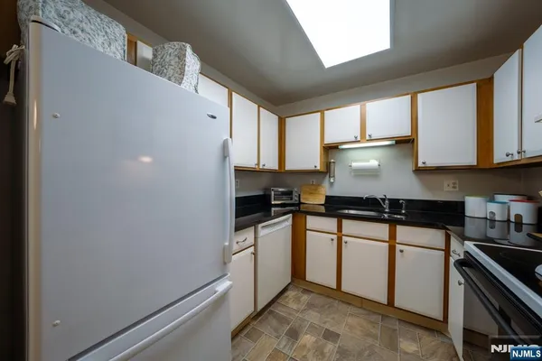 a kitchen with granite countertop white cabinets and white appliances