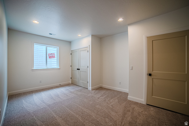 223 South Cottonwood Road, Unit 7501 Vineyard, UT 84059 - Photo 7 of 45 Carpeted room featuring recessed lighting, a neutral wall color, a white-framed window with white blinds, a bi-fold closet door, and a solid panel door with black hardware