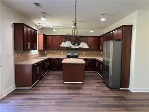 a kitchen with kitchen island granite countertop wooden floors stainless steel appliances a sink and a center island