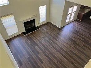 an empty room with wooden floor fireplace and windows