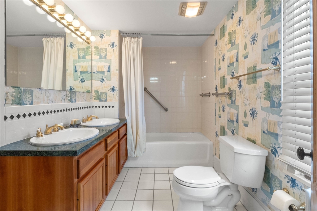 2 High Street Marblehead, MA 01945 - Photo 20 of 35 a bathroom with a granite countertop sink a toilet a mirror a bathtub and shower