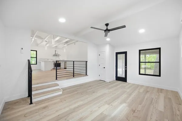 a view of empty room with wooden floor and fan
