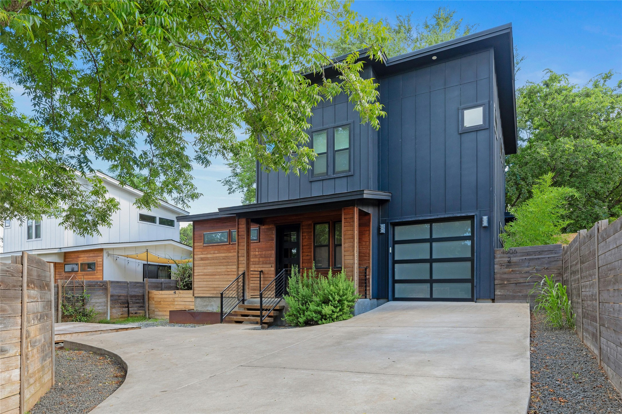 4606 Ledesma Road, Unit 2 Austin, TX 78721 - Photo 3 of 33 Modern architecture with wood and dark paneling, framed by lush foliage.