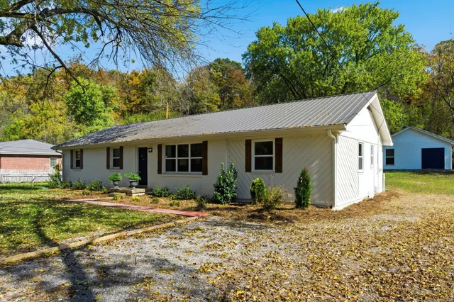 a backyard of a house with table and chairs under an umbrella