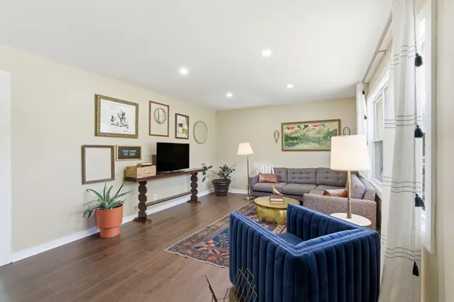 a bedroom with a bed a chair and potted plant on the dresser