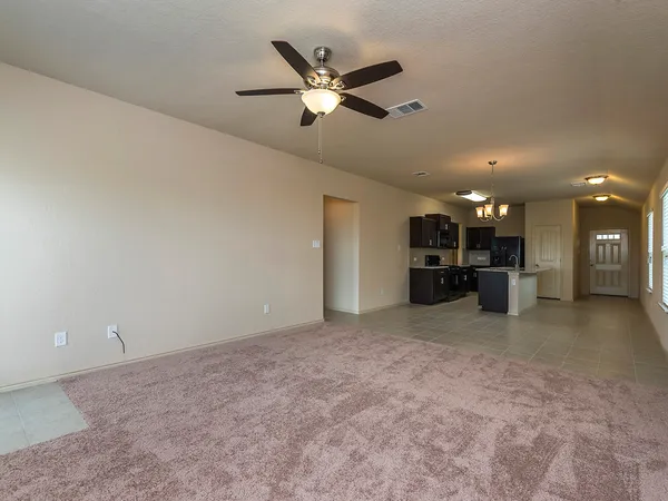 a view of a livingroom with a ceiling fan and kitchen view