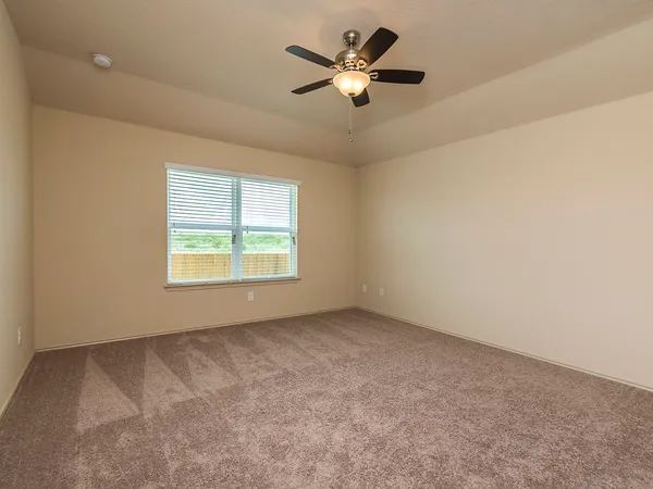 an empty room with a window and a fan