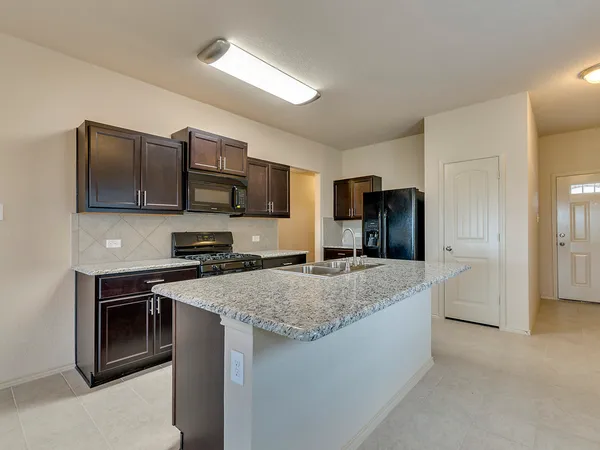 a kitchen with stainless steel appliances granite countertop a sink stove microwave and refrigerator
