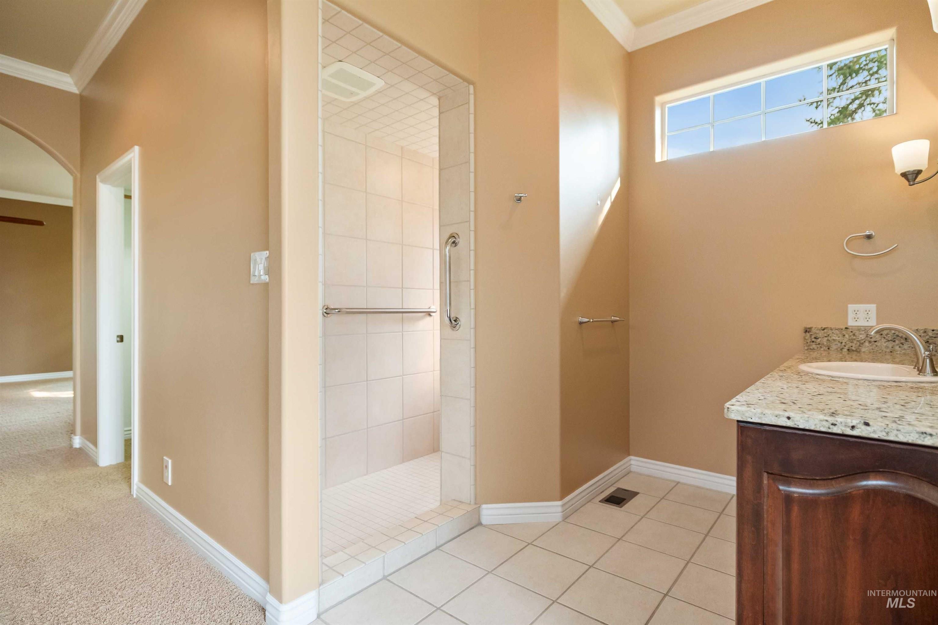 3404 Ridge Line Drive Kimberly, ID 83341 - Photo 21 of 50 Bathroom featuring a glass-enclosed shower with subway tile surround, single vanity with a granite countertop and integrated sink, wood-finish cabinetry, and a high transom window