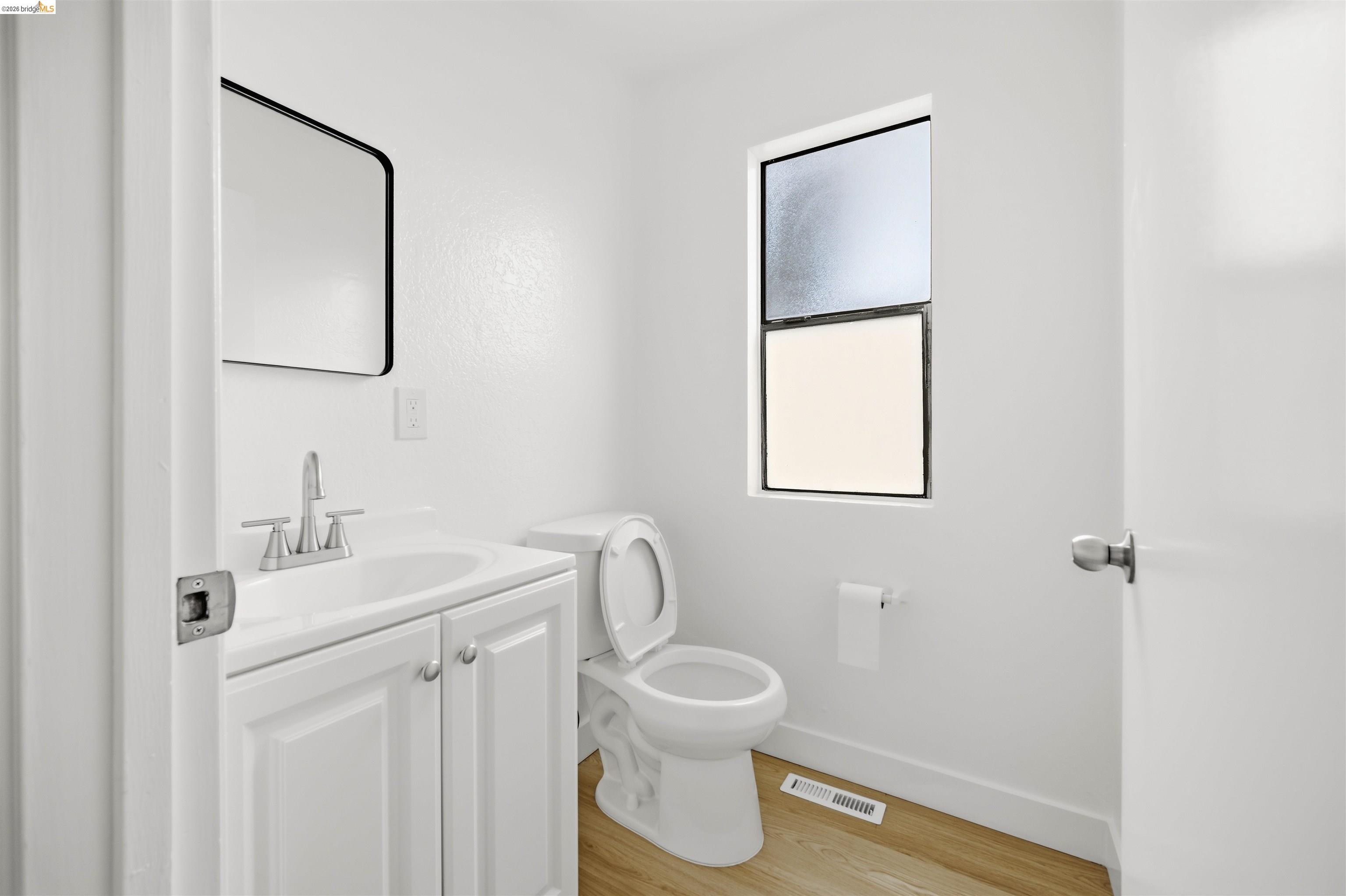 10933 Julius Street, Unit D Oakland, CA 94605 - Photo 7 of 28 a bathroom with a toilet sink and mirror
