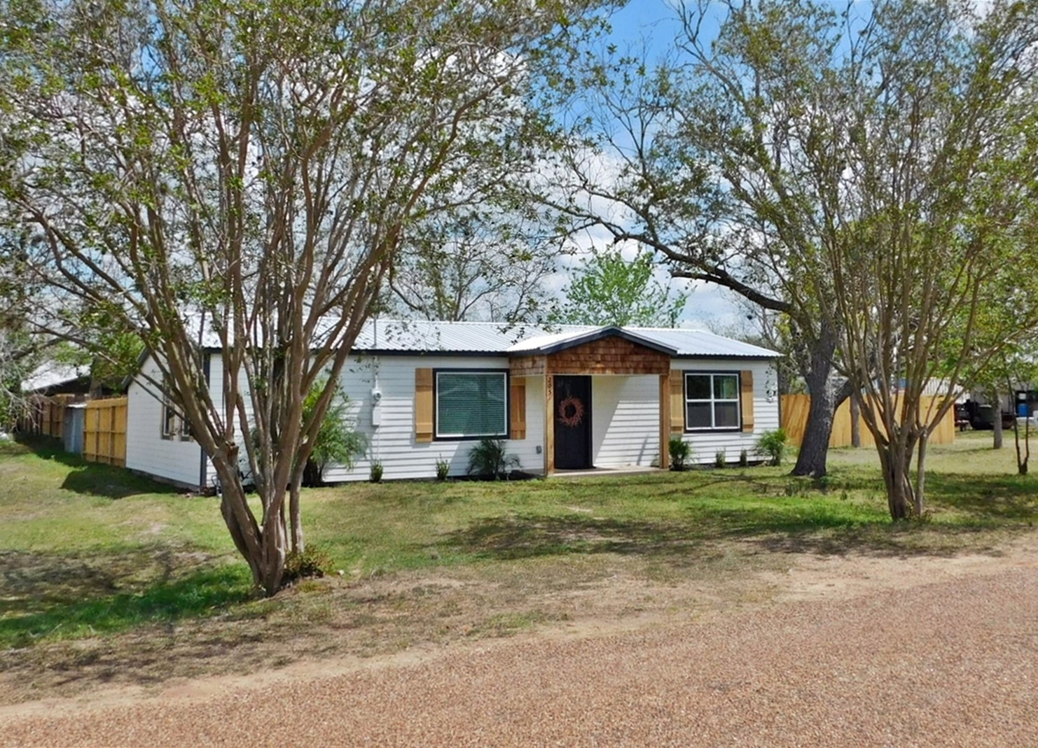 205 East Train Street Ellinger, TX 78938 - Photo 1 of 27 a white house that has a tree in front of it