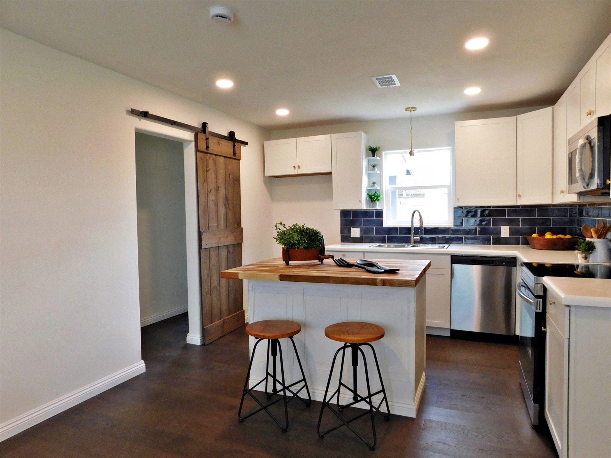 205 East Train Street Ellinger, TX 78938 - Photo 7 of 27 a kitchen with kitchen island granite countertop wooden floors and stainless steel appliances