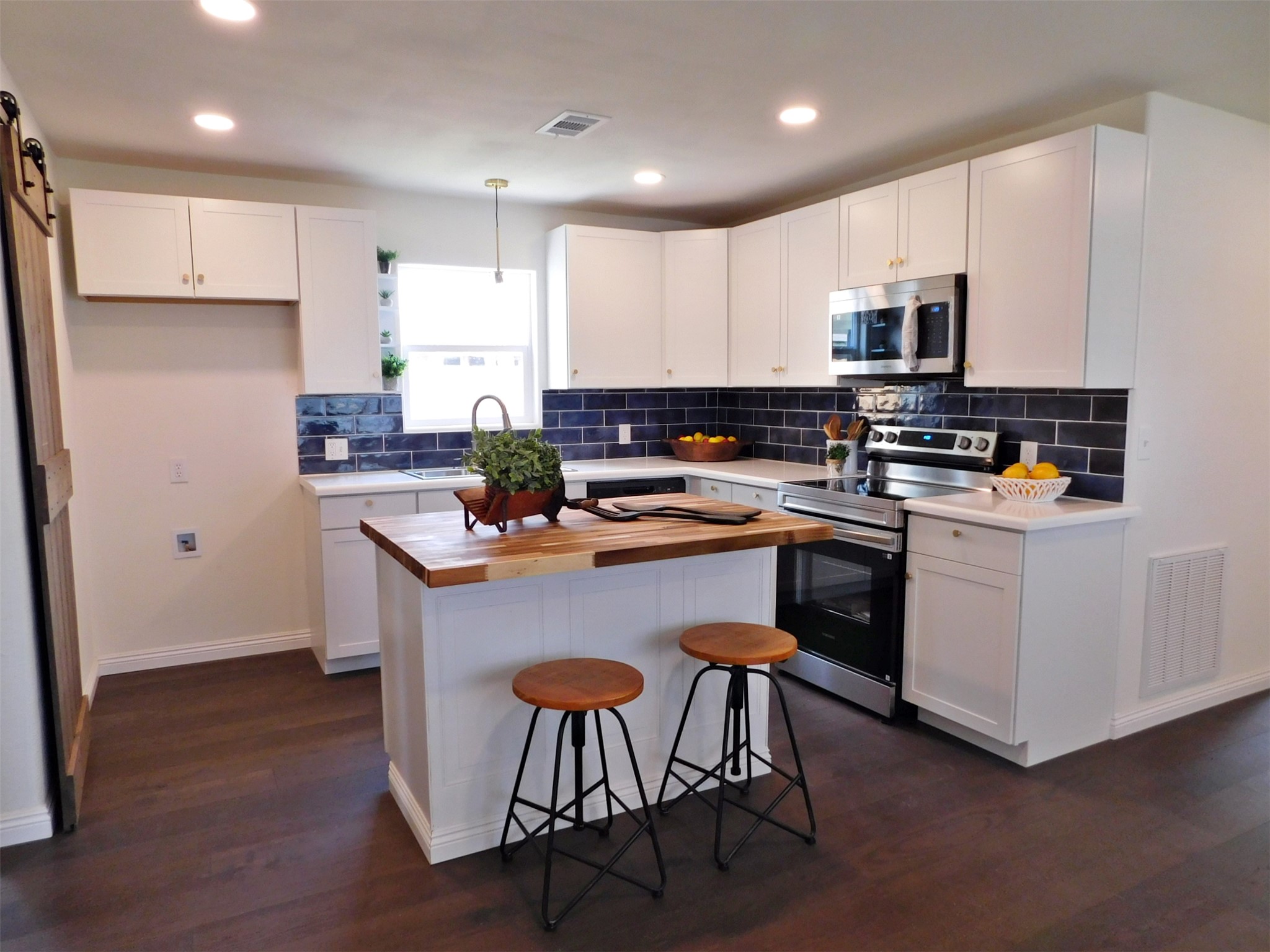 205 East Train Street Ellinger, TX 78938 - Photo 9 of 27 a kitchen with stainless steel appliances a sink a stove a refrigerator cabinets and wooden floor