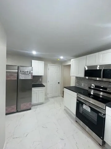 a large kitchen with stainless steel appliances a stove a sink and a refrigerator