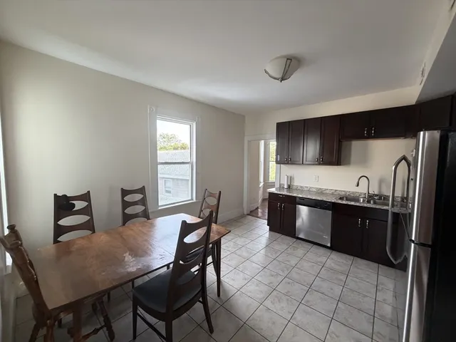 a large kitchen with granite countertop a stove a sink dishwasher a dining table and chairs