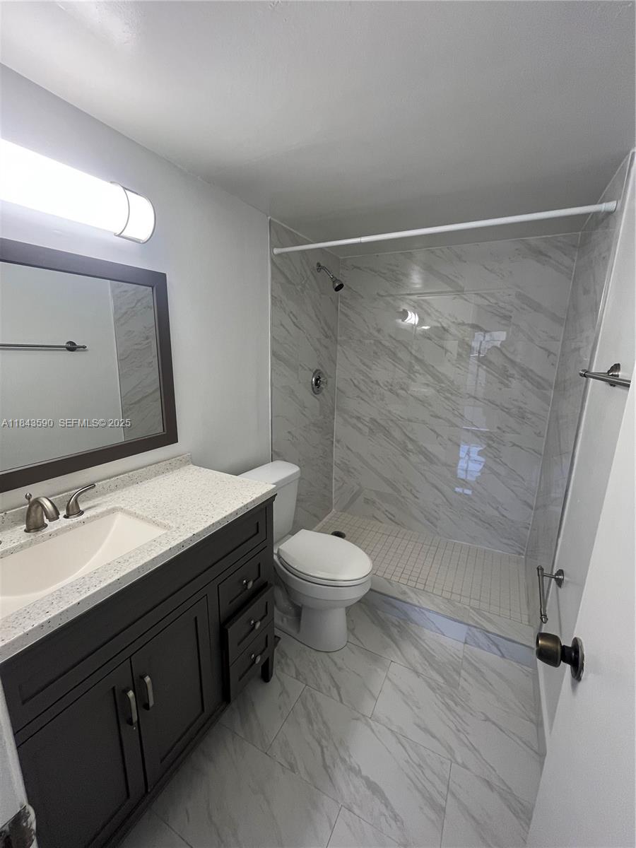 7430 Southwest 153rd Place, Unit 1061 Miami, FL 33193 - Photo 13 of 42 a bathroom with a granite countertop sink toilet a mirror and shower