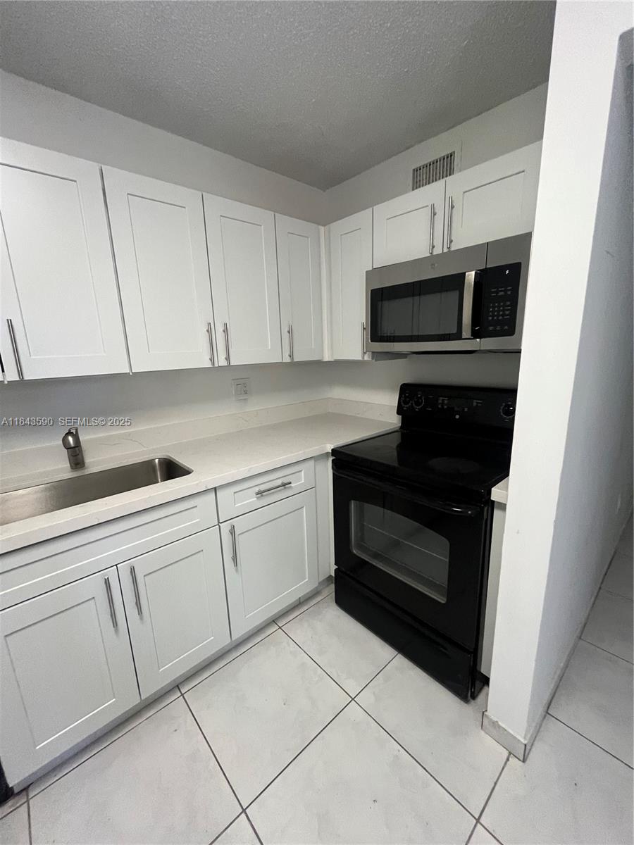 7430 Southwest 153rd Place, Unit 1061 Miami, FL 33193 - Photo 36 of 42 a kitchen with white cabinets and stainless steel appliances