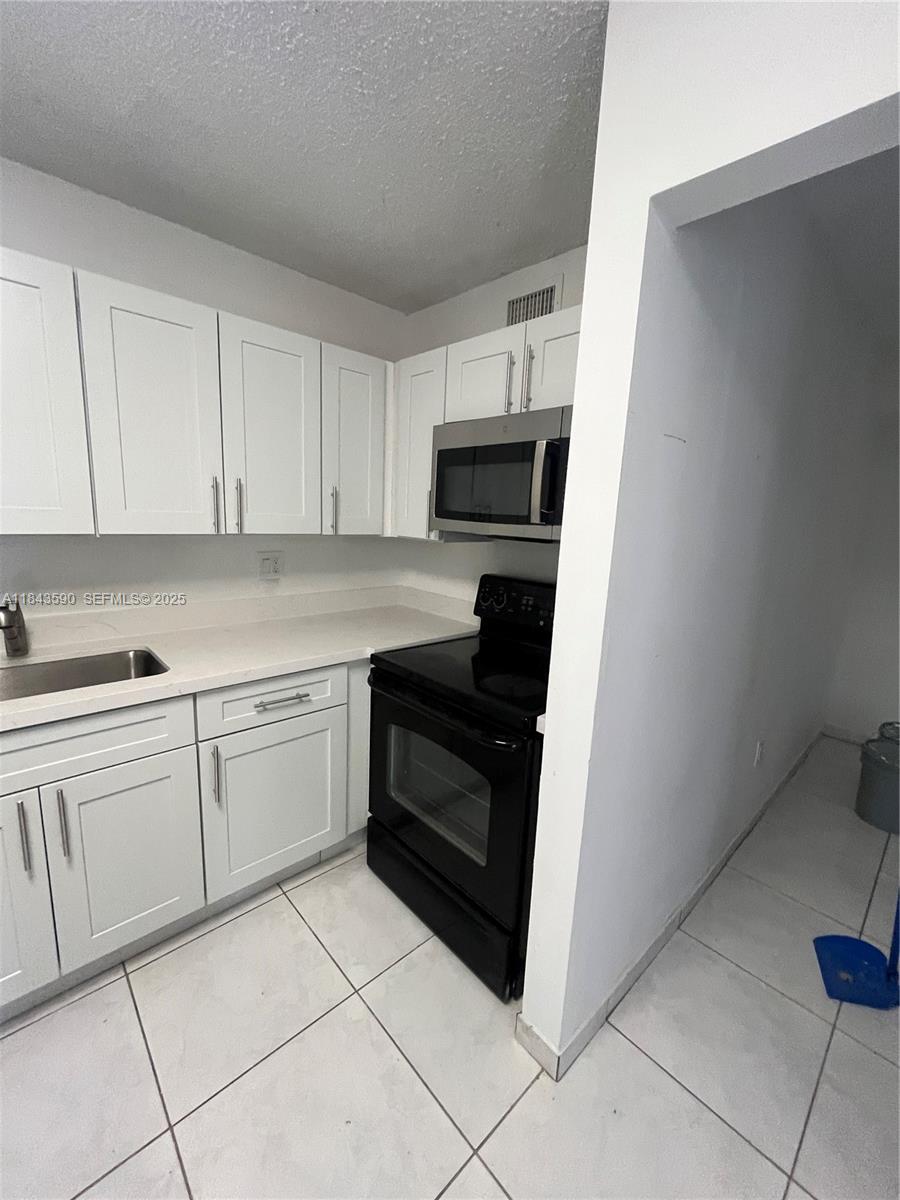 7430 Southwest 153rd Place, Unit 1061 Miami, FL 33193 - Photo 41 of 42 a kitchen with a stove top oven and cabinets