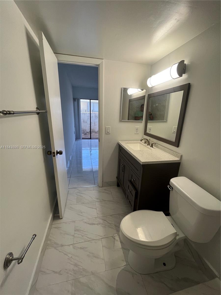 7430 Southwest 153rd Place, Unit 1061 Miami, FL 33193 - Photo 5 of 42 a white toilet sitting next to a bathroom sink and a mirror