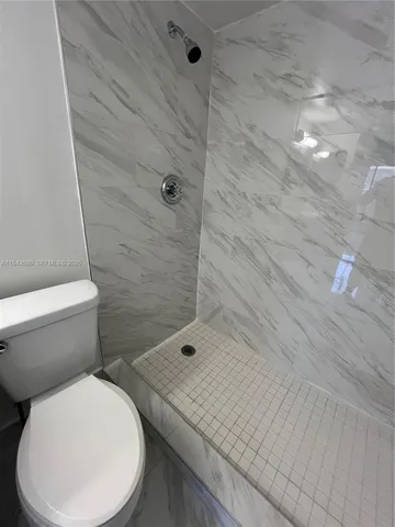 a bathroom with a granite countertop sink toilet a mirror and shower