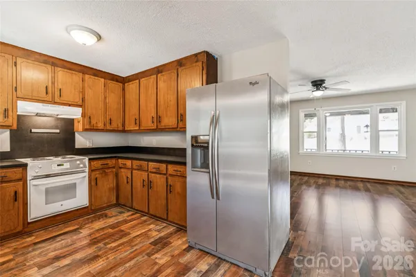 a kitchen with stainless steel appliances granite countertop a refrigerator a stove and a sink with wooden floor