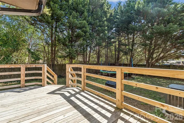 a view of a deck with wooden floor and fence next to a yard