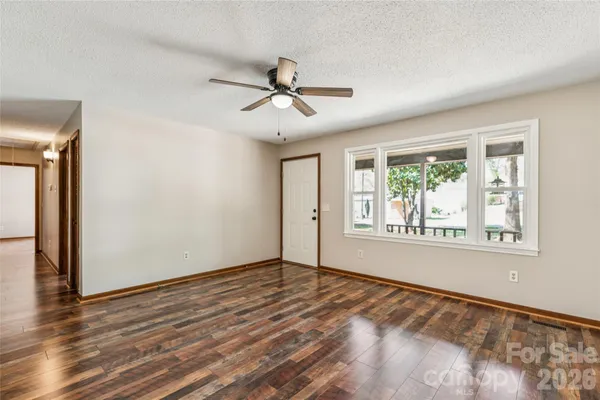a view of an empty room with a window and wooden floor